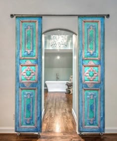 an open door leading to a bathroom with a tub and chandelier in the background