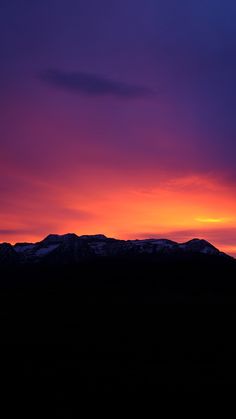 the sun is setting over some mountains with snow on them and purple clouds in the sky