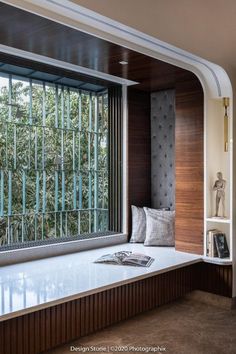 a window seat in the corner of a room with books on it and a book shelf