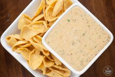 a white bowl filled with tortilla chips next to a container of salsa dip