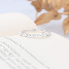 an open book with a ring on top of it and leaves in the back ground