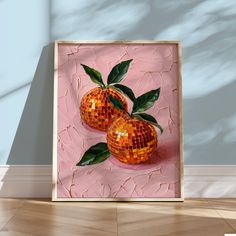 two oranges with green leaves are in a wooden frame