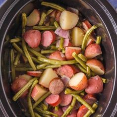 a crock pot filled with potatoes, green beans and sausage