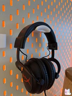 a pair of headphones hanging on a wall in front of a white and orange background