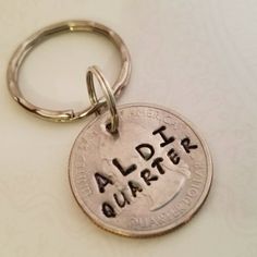 a silver coin keychain with the word alder quarter on it's side