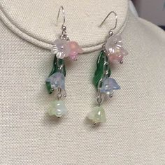 Pastel dangle chain flowers bring in cheerful days ahead.  They are all glass except for the little flower at top as an accent. A dark green glass leaves brings out the color of the flowers.  In side of each flower is a Swarovski crystal. They measure about 1 3/4 inches from below the ear hooks. What a beautiful pair of sunny delightful pastel glass Bell earrings to wear, ~~Anytime    ENJOY Use ear plugs to not loose~! Pink Dangle Flower Earrings, Whimsical Dangle Flower Earrings, Whimsical Dangle Jewelry With Flower Charm, Whimsical Pink Dangle Flower Earrings, Spring Sterling Silver Dangle Jewelry, Sterling Silver Dangle Jewelry For Spring, Whimsical Flower-shaped Hypoallergenic Jewelry, Whimsical Hypoallergenic Flower Jewelry, Whimsical Dangle Earrings With Flower Charm