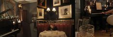 a woman sitting at a table in front of a piano and pictures on the wall