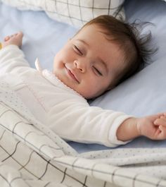 a baby laying on top of a bed next to pillows