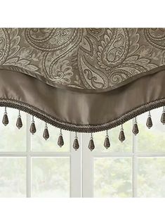 a window curtain with tassels hanging from it's valance, in front of a window