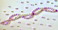 a beaded name necklace with beads and confetti around it on a white surface