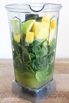 a blender filled with fruit and vegetables on top of a wooden table