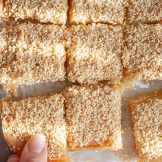 someone is holding their hand over some rice krispy kreme squares on a sheet of wax paper