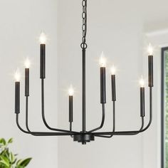 a black chandelier with eight candles hanging from it's centerpiece in a white room