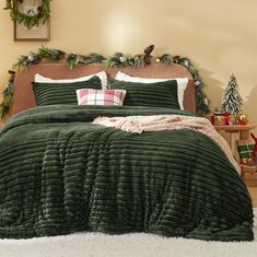 a bed with green comforter and pillows in a room decorated for the holiday season