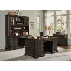 an office desk with two drawers and a computer monitor on it, in front of a large window