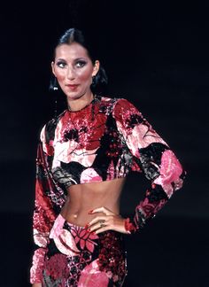 a woman in a red and black dress with her hands on her hips, posing for the camera