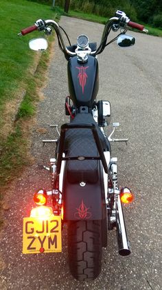 the motorcycle is parked on the side of the road with its rear light turned on