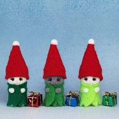 three small stuffed animals with red hats and green clothes, one holding a present box