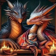 two dragon sitting next to each other with candles in front of them on a table