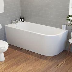 a white bath tub sitting on top of a wooden floor next to a toilet and sink