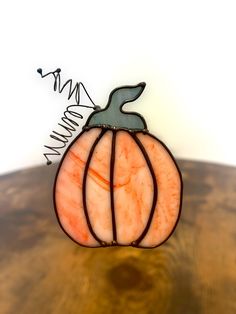 a stained glass pumpkin sitting on top of a wooden table