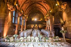 the tables are set up in an old church for a wedding reception with white and green floral centerpieces