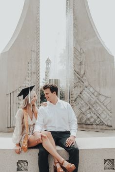 a man and woman are sitting on a wall