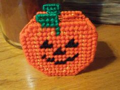 an orange purse with a face on it sitting on a table next to a jar