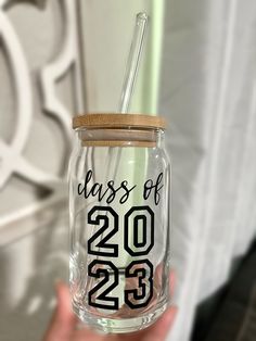 a hand holding a glass jar with a straw in it that says class of 2013