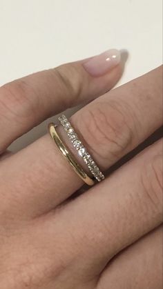 a woman's hand wearing a gold ring with three diamonds on the middle finger