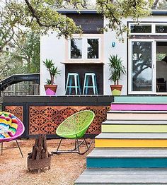 several colorful chairs are sitting on the steps in front of a house with barstools