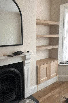 an empty living room with a fireplace, mirror and bookshelf in the corner