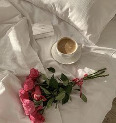 a cup of coffee and some flowers on a bed