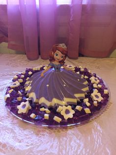 there is a cake that looks like a princess on the table with purple frosting