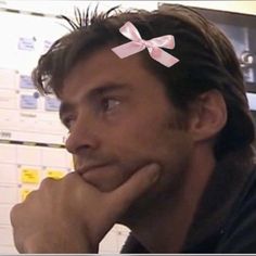 a man with a pink bow on his head sitting in front of a white board