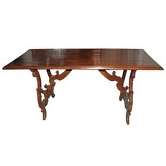 a wooden table with ornate carvings on the top and bottom, against a white background