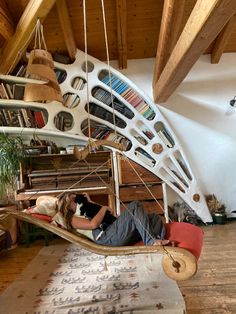 a woman laying in a hammock with bookshelves on the wall behind her