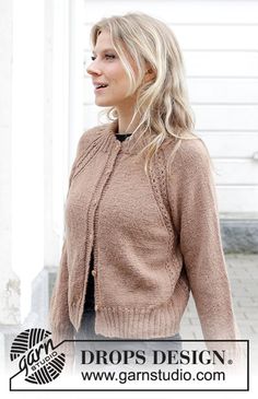 a woman wearing a brown sweater and black pants standing in front of a white building