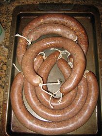 several large sausages are on a baking sheet in the oven, ready to be cooked