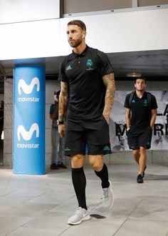 a man in black shirt and shorts walking on sidewalk