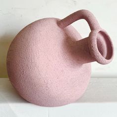 a pink vase sitting on top of a white table