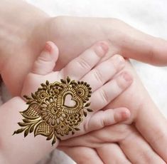 a woman holding a baby's hand with henna tattoos on it and the words,