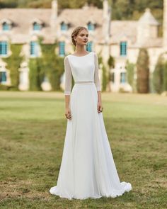 a woman in a white wedding dress standing on the grass