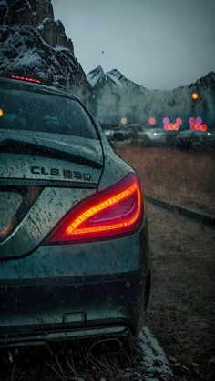 the back end of a car parked in front of a mountain with snow on it