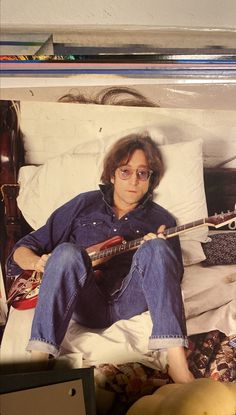 a man sitting on top of a bed with a guitar in his lap next to a banana