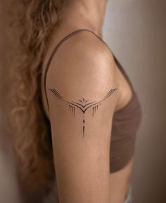 the back of a woman's shoulder with an arrow tattoo on her left arm