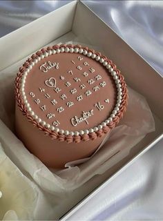 a birthday cake in a box with pearls on the top and writing on the side