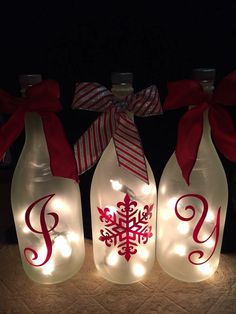 three wine bottles with christmas lights on them