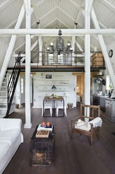 a living room filled with furniture next to a white kitchen and dining room table on top of a hard wood floor