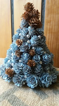 a blue christmas tree made out of pine cones